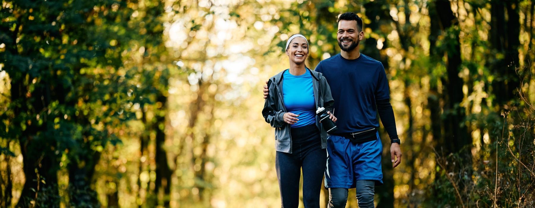 a man and woman walking on a path in the woods